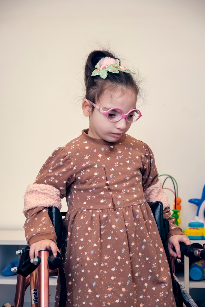 a little girl in a brown dress and pink glasses